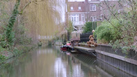 Ruhiger,-Von-Bäumen-Gesäumter-Kanalabschnitt-In-Utrecht,-Niederlande,-Mit-Reflexionen-Auf-Dem-Wasser-Und-Dem-Verkehr,-Der-In-Der-Ferne-über-Eine-Brücke-Fährt