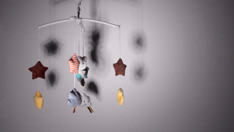 Lullaby-Musical-Crib-Mobile-With-Stars,-Clouds,-Moon,-And-Bear-Spinning-With-Shadows-On-Wall-Inside-Nursery-Room