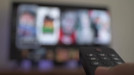 Close-up-shot-of-person-using-tv-remote-to-select-what-to-watch-on-tv