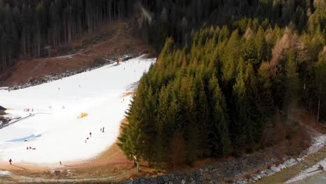 Slow-motion-downward-aerial-tilt-of-a-dense-forest-and-ski-area-in-the-Italian-Alps