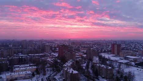 Aerial-view-of-apartment-houses-in-winter,-with-the-pink-epic-sunrise-sky,-snowy-environment,-flying-round-above-apartments,-parallax,-in-Lithuania,-looks-like-the-end-of-the-world