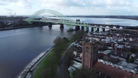 Aerial-descent-over-Widnes-small-town-Jubilee-bridge-church-rooftops-neighbourhood-North-West-England