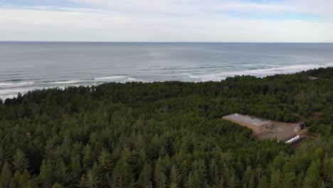 Industrial-Building-In-The-Middle-Of-Dense-Forest-By-The-Beach---Aerial-Drone-Shot