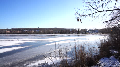 Still-shot-of-a-frozen-lake-with-cars-and-smoke-in-the-back