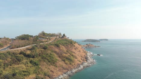 Windmill-Viewpoint-over-Steep-hill-carrying-the-road-to-Promphet-Cape,-in-Phuket,-Thailand---Aerial-Low-angle-wide-Fly-over-shot