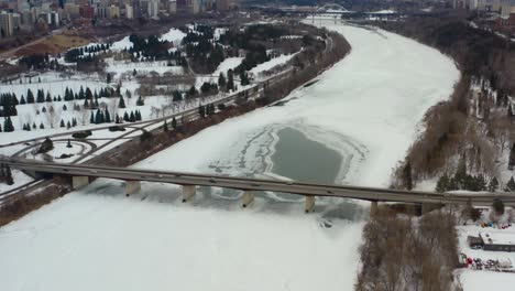 Aerial-birds-eye-view-fly-over-Groat-Rd-NW-Bridge-snow-covered-icy-North-Saskatchewan-River-on-a-winter-gloomy-afternoon-surrounded-by-quiet-golf-courses-and-parks-on-each-side-Edmonton-Alberta-3-7