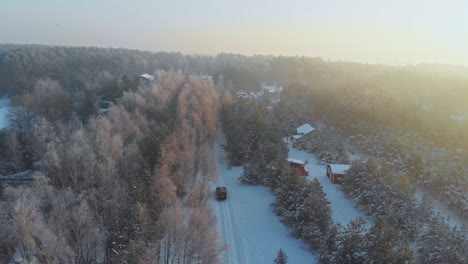 Drone-shot-of-a-car-driving-in-a-snowed-forest