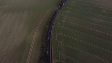 A-drone-reveal-shot-showing-a-beautiful-country-road-with-greenfields-and-open-space