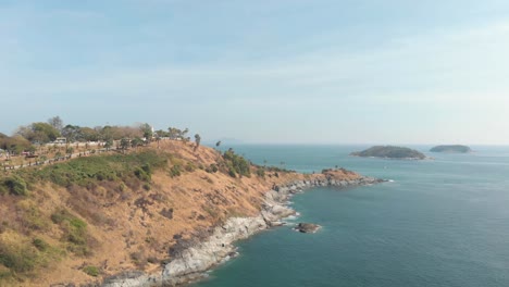 Steep-barren-hill-connecting-to-Promthep-Cape-next-to-Yanui-Beach-in-Phuket,-Thailand---Aerial-Panoramic-low-angle-shot