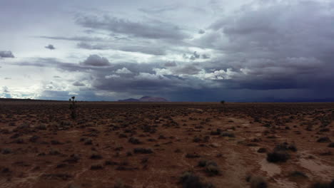 Un-Día-Raro-En-El-Desierto-De-Mojave-Con-Nubes-De-Lluvia-Reunidas-Sobre-Las-Montañas-Y-La-Cuenca---Avance-Aéreo