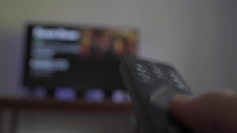 Person-using-remote-to-sift-through-shows-on-TV