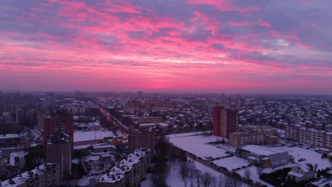 Aerial-view-of-apartment-houses-in-winter,-with-the-pink-epic-sunrise-sky,-snowy-environment,-flying-straight-above-apartments,-zoom-in,-in-Lithuania,-looks-like-the-end-of-the-world