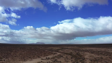 Cumulus-clouds-watch-over-the-Mojave-Desert's-rugged-landscape---sliding-aerial-view
