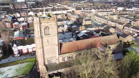 Aerial-rotate-left-view-industrial-small-town-frosty-church-rooftops-neighbourhood-North-West-England
