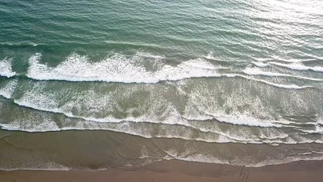 Aerial-top-down-view-of-ocean-waves-crashing-on-sandy-beach