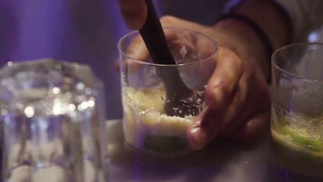 Barman-preparing-drink-with-mint,-yellow-sugar-and-lime-in-a-bar
