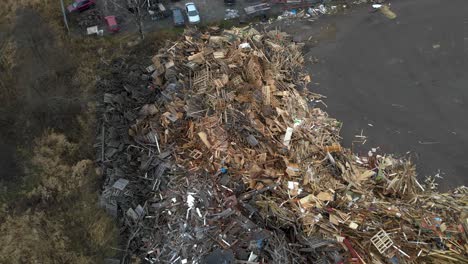 Aerial-top-down-view-rotating-over-huge-dumpsite-filled-with-pile-of-wooden-and-bulky-waste-made-up-of-light-and-dark-euro-pallets