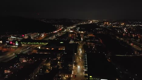 Stunning-night-time-aerial-of-downtown-Partille-and-European-route-E6-highway-with-illuminated-skyline,-buildings-and-street-lights-in-Gothenburg-City,-Sweden