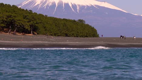 Slow-tilt-up-over-beautiful-beach-and-Mount-Fuji-with-many-tourists