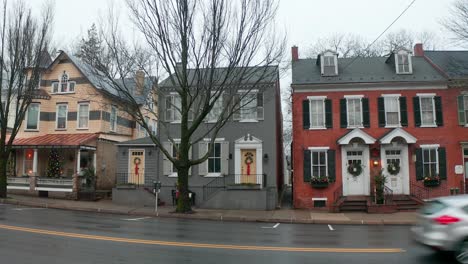 Colonial-Victorian-homes-decorated-for-Christmas-holidays-in-small-town-in-USA-as-traffic-passes-by