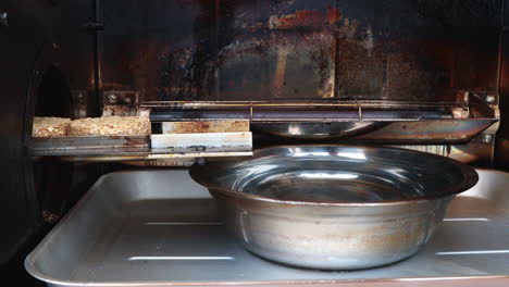 Close-Up-Of-Wood-Puck-Smoker-With-A-Stainless-Basin-Of-Hot-Water