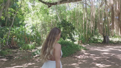 Natural-long-blonde-haired-girl-walk-relaxed-under-banyan-tree,-Maui