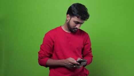 young-crazy-man-holding-his-smart-phone-celular-against-green-chroma-key-background