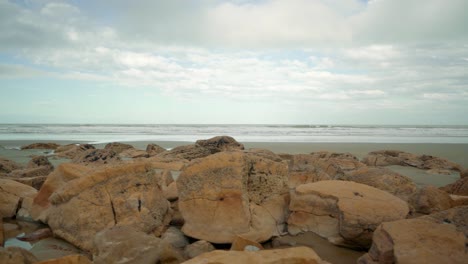 Sliding-right-to-left-shot-of-rocks-on-a-beach-in-New-Zealand