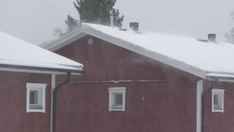 Heavy-Snowfall-on-Traditional-Red-Swedish-House,-Establishing,-Medium