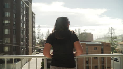 South-African-Indian-Woman-Standing-And-Leaning-On-The-Balcony-Of-Apartment-Enjoying-The-View-Of-Port-Macquarie-Town-In-New-South-Wales,-Australia