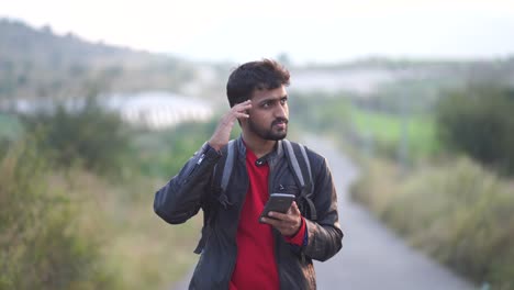 young-man-with-beard,-traveling-in-the-mountains-and-looking-at-his-mobile-phone