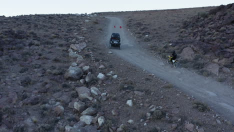 Dirt-bike-cruising-up-gravel-road-in-rocky-desert-landscape