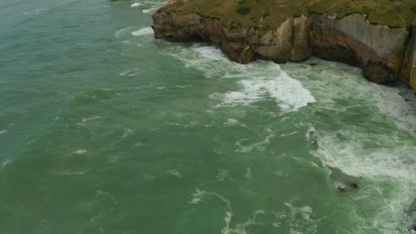 Aerial-top-down,-orbiting-shot-of-cliffs-along-the-coastline-in-New-Zealand-during-the-day