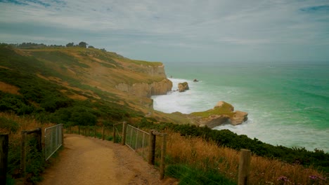 Handheld-shot-of-the-cliffs-along-the-coastline-in-New-Zealand-while-walking-down-a-path-on-a-slope