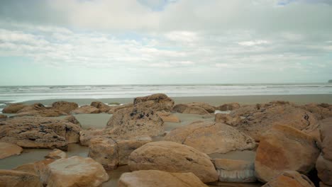 Handheld-orbiting-shot-of-boulders-on-the-beach-in-New-Zealand-during-the-day