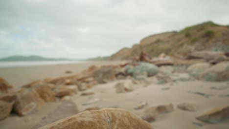 Aufsteigende-Aufschlussreiche-Aufnahme-Eines-Felsigen-Strandes-Mit-Einem-Felsbrocken-Im-Vordergrund-In-Neuseeland