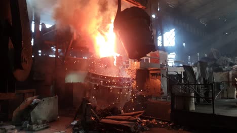 Hot-liquid-molten-metal-being-poured-from-ladle-into-casting-flask-at-steel-fabrication-industry