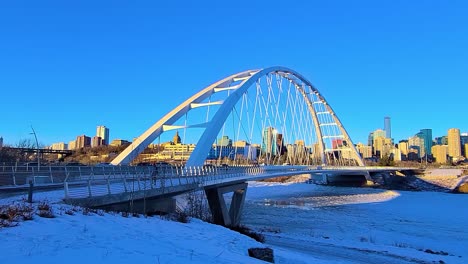 2-2-4k-Zeitraffer-Perfekte-Schleife-Sonniger-Winter-Moderner-Weißer-Walter-Dale-Brückenverkehr-Und-Menschen,-Die-Den-Klobigen,-Schneebedeckten-North-Saskatchewan-River-Mit-Einem-Horizont-Der-Innenstadt-Von-Edmonton-überqueren