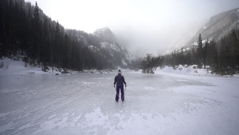 Female-Hiker-Walking-on-Snow-and-Ice-of-Frozen-Lake-in-Cold-Winter-Day