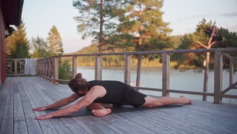 Hombre-Caucásico-Estirándose-En-Una-Alfombra-De-Yoga-Con-Vista-Al-Lago-En-Noruega