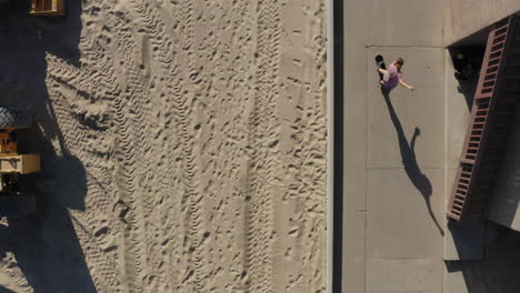 Skateboarding-on-sidewalk-near-sandy-Seal-Beach-is-Los-Angeles,-aerial-view