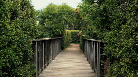 POV-Of-A-Person-Walking-A-Wooden-Bridge-To-Hedge-Maze