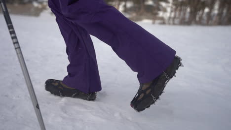 Legs-of-Hikers-Walking-on-Snow-With-Boots-in-Icetrekkers-Chains,-Close-Up