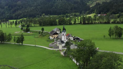 Aerial-view-of-church-with-cemetery,-Jezersko,-Slovenia,-a-small-rural-town-in-European-Alps