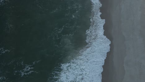Top-Down-Aerial-View-Of-Beach-With-Waves-Crashing-Into-The-Sand---static,-slow-motion