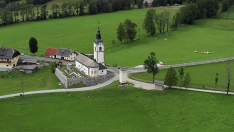 Aerial-view-of-church-with-cemetery,-Jezersko,-Slovenia,-a-small-rural-town-in-European-Alps