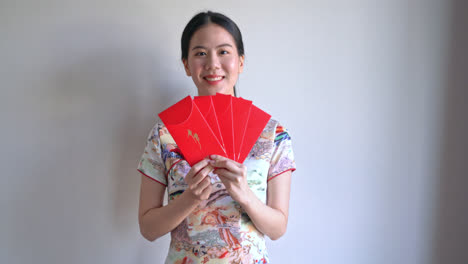 Schöne-Asiatische-Frau-Trägt-Chinesisches-Traditionelles-Kleid-Mit-Rotem-Umschlag-Oder-Rotem-Paket