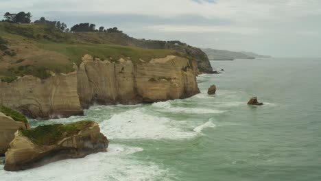 Orbiting-aerial-shot-of-rock-formations-and-cliffs-along-the-coastline-in-New-Zealand