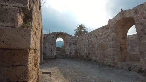 Ruinas-De-Las-Murallas-Del-Castillo-De-Kyrenia-Y-Arcadas-Antiguas-Durante-La-Noche-De-Oro-En-Chipre---Amplia-Toma-De-Cardán