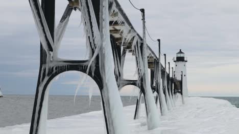Ein-Leuchtturm-Blickt-über-Eine-Eisbrücke-Am-Michigansee-In-Manistee,-Michigan
